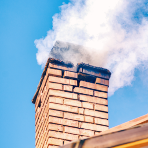 masonry chimney with a crack near the top and smoke coming out