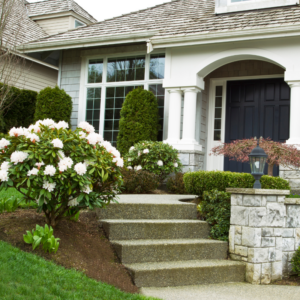 a white house with flowers and concrete steps leading up to it
